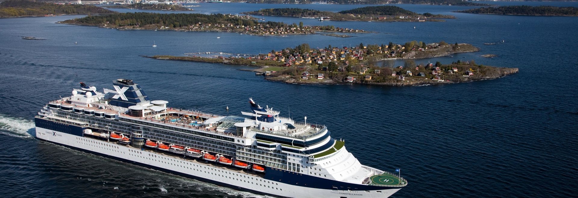 Aerial of the Celebrity Constellation sailing near a port city