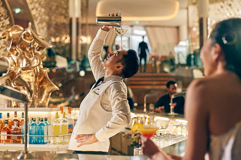 A bartender pouring a martini into a glass on his forehead